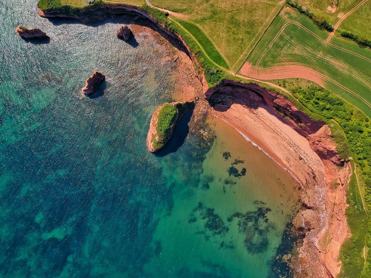 Aluguer de Cabana Devon 2 Vista aérea das falésias e águas turquesa de Ladram Bay em Devon