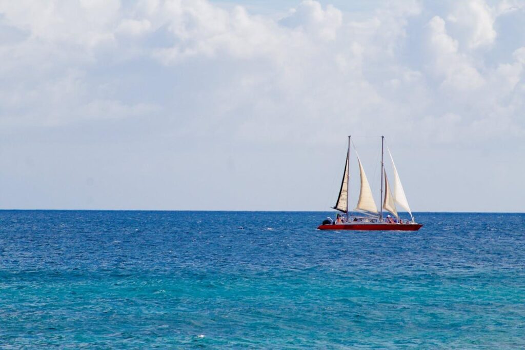 Beautiful red sailing yacht with three white sails in the ocean