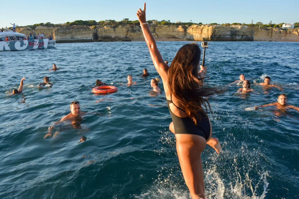 Girl jumping into the sea during a boat party in Portimão
