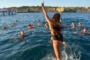 Mädchen springt bei einer Bootsfeier in Portimão ins Meer